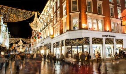 Festive city street with families enjoying holiday lights and shopping at night.