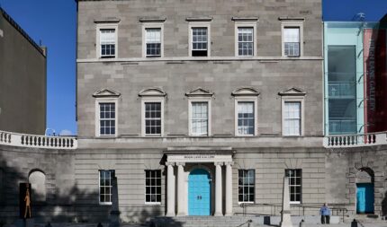 Grand historical building entrance with blue doors under a clear sky.