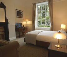 Cosy guesthouse room with double bed, charming decor, and a lush garden view.