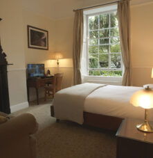 Cosy guesthouse room with double bed, charming decor, and a lush garden view.