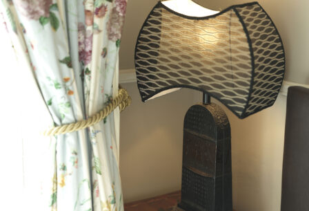 Elegant lamp and floral curtains create a warm, inviting atmosphere in Harveys Guesthouse room.