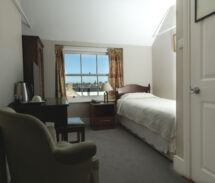 Cosy single room with window view at Harveys Guesthouse, welcoming decor, and ample sunlight.