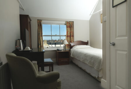 Cosy single room with window view at Harveys Guesthouse, welcoming decor, and ample sunlight.