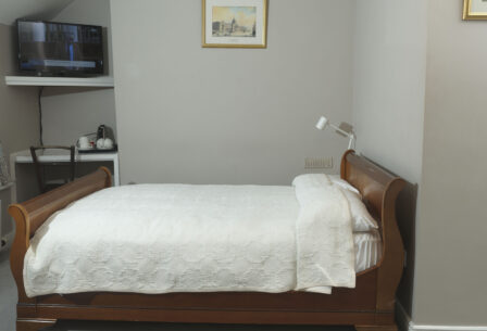 Cosy guest room with wooden bed, TV, and tea-making set, creating a welcoming atmosphere.