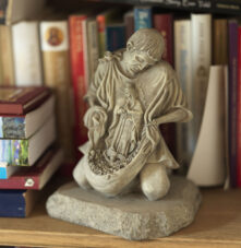 Cosy bookshelf with travel guides and a charming statue, adding warmth to Harveys Guesthouse.