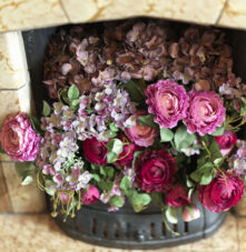 Vibrant flowers adorn a cosy fireplace at Harveys Guesthouse, creating a warm, inviting atmosphere.