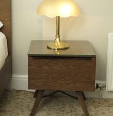Elegant bedside lamp on a wooden nightstand in a cosy guesthouse room.