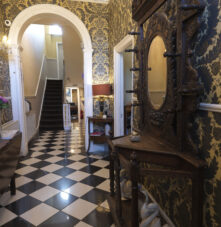 Elegant entryway of Harveys Guesthouse with ornate wallpaper and vintage decor.