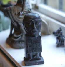 A sunlit windowsill with diverse sculptures and a photo, evoking warmth and cultural charm.