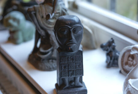 A sunlit windowsill with diverse sculptures and a photo, evoking warmth and cultural charm.