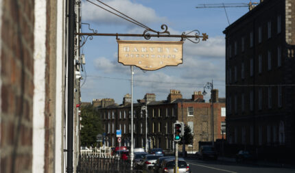 Harveys Guesthouse sign on a sunny street with historic buildings.