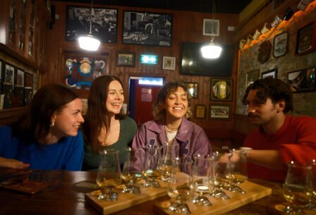 Group in warm pub, enjoying drinks with laughter.