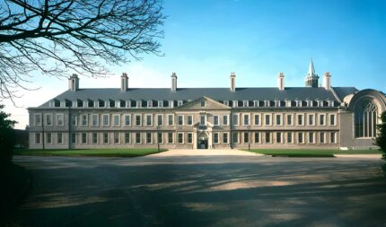 Grand Harveys Guesthouse exterior with large windows and lush green lawn under clear blue sky.