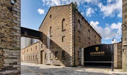 Historic cobblestone street by Guinness brewery in Dublin under a blue sky.